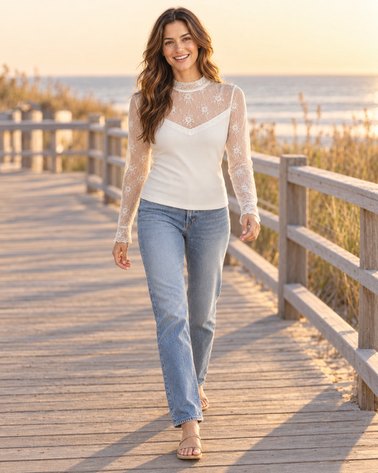 Model walking in white lace mesh long-sleeve top with sheer floral lace yoke and sleeves, styled with light denim