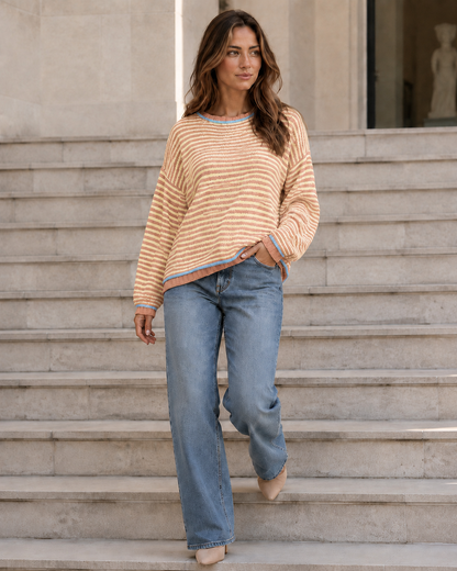 Kira Striped Dropped-Shoulder Sweater in Orange-Red, walking on steps